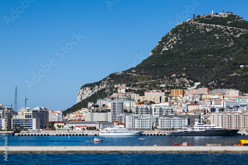 View from the sea to the port of Gibraltar. Bay, buildings, moored ships and yachts and the mountain.