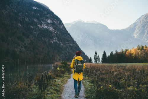 Obraz na plátně girl in a yellow jacket with a backpack in a red hat and glasses stands with her