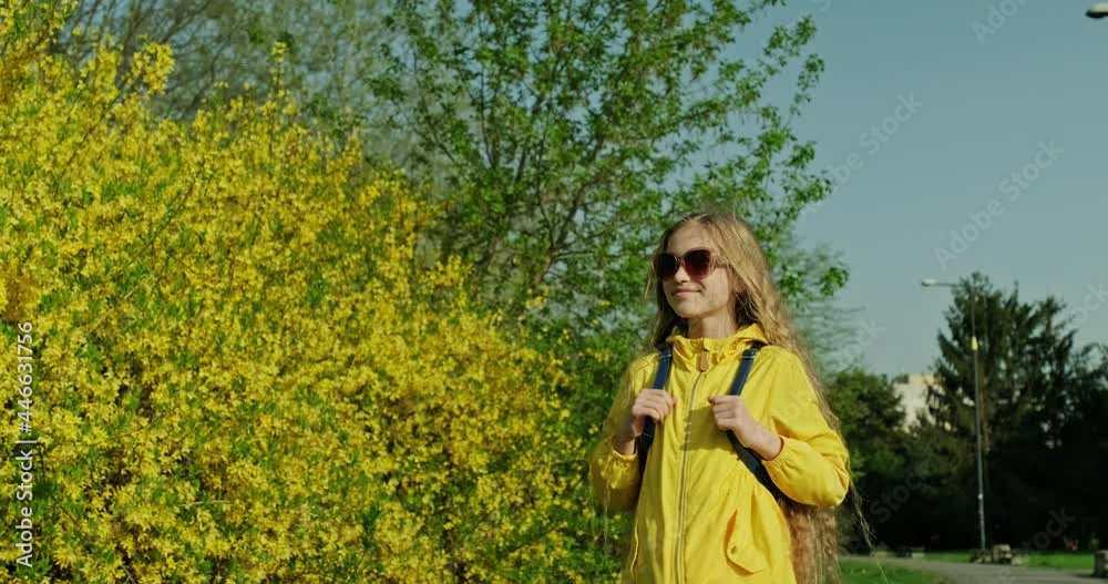 Preteen girl 10s weared in yellow jacket walking on the park. Long hair fluttering in the wind Preteen girl 10s weared in yellow jacket walking on the park. Long hair fluttering in the wind