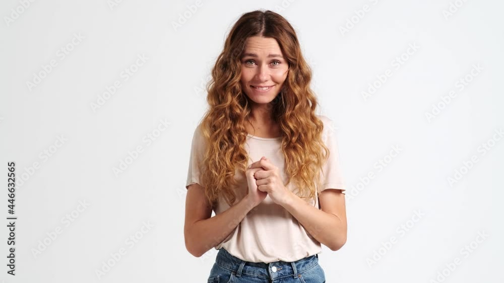 A positive woman is doing heartwarming gesture isolated over a white wall in the studio A positive woman is doing heartwarming gesture isolated over a white wall in the studio