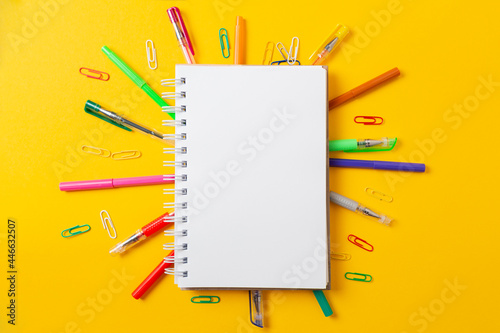 Back to school. Composition with notepad and multicolored pencils, yellow desktop table background. Flat lay, mock up. Copy space. Concept of education