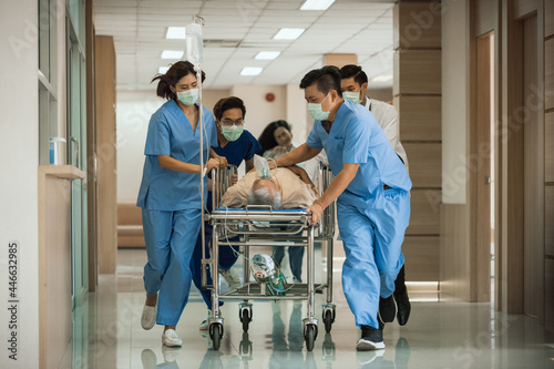 Emergency Department: Group of Doctors, Nurses, Paramedics Push Gurney, Stretcher with Seriously trauma Patient towards the Operating Room. Group of Asian staff rushing to save the people