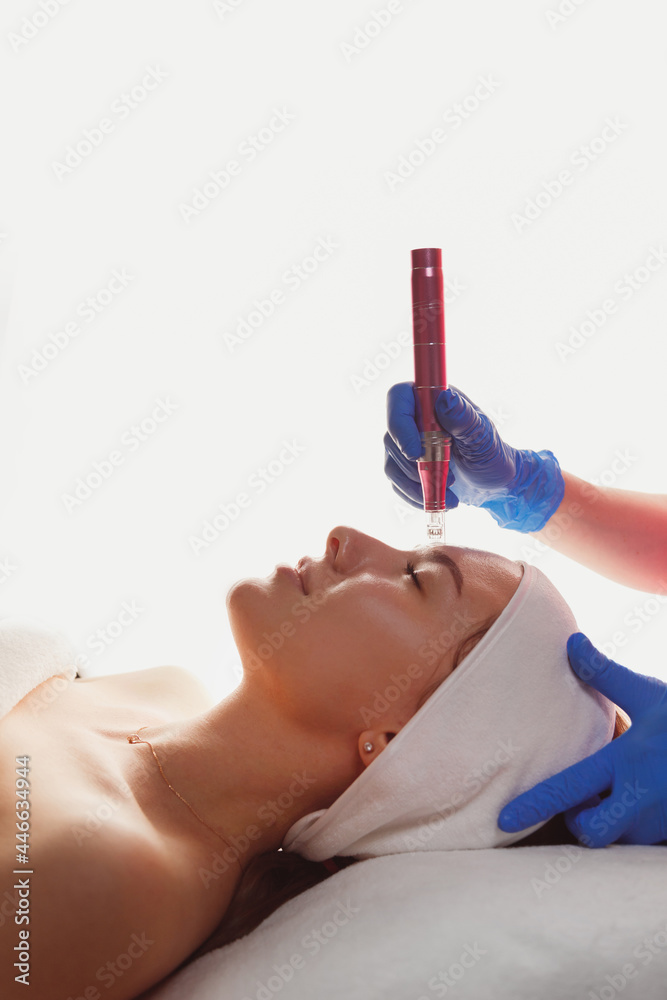 Professional cosmetology. Beautician is using dermapen on woman face skin, side view. Skin beauty and health