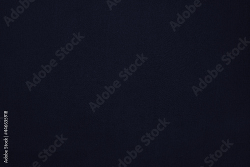 Texture of a dark blue flat fabric of polyester material. Fabric background in dark blue tone.