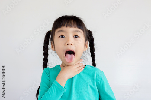 asian child with pigtails hair style touch her neck and show her tongue like she has sore throat photo