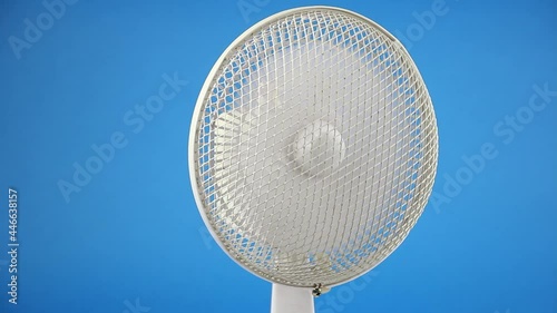 rotating retro fan ventilator in center of blue screen background, vintage electrical conditioning and air cooling, front view