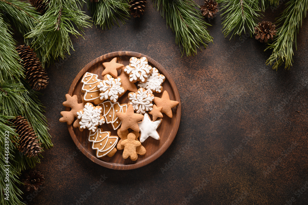 Christmas homemade assorted glazed cookies in wooden plate on brown background. New Year holiday treats. Top view. Xmas greeting card. Copy space.