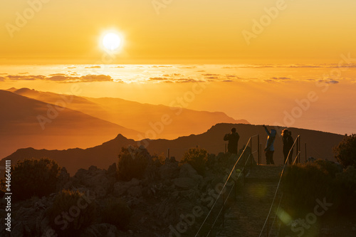 Tourists photographing sunset with smartphone from Pico Ruivo mountain peak, Madeira, Portugal photo
