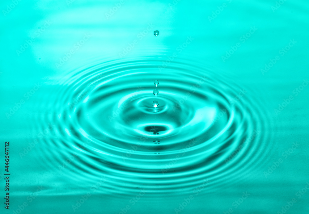falling drops on the water surface, splash, ripples on the water, turquoise color falling drops on the water surface, splash, ripples on the water, turquoise color