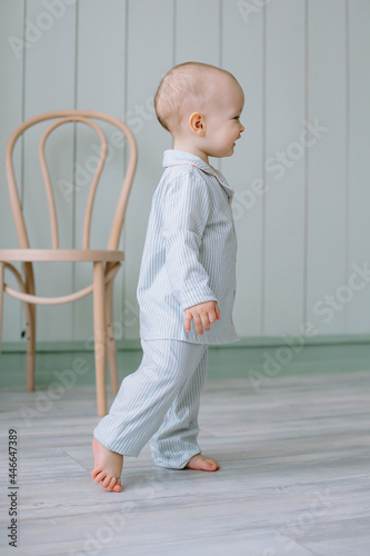 small child of European appearance, a boy with blue eyes in pajamas, walks around the room Children's room for children