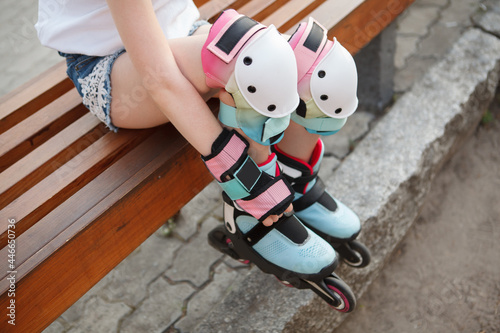Cropped shot of unrecognizable girl wearing colorful knee pads and rollerblades photo