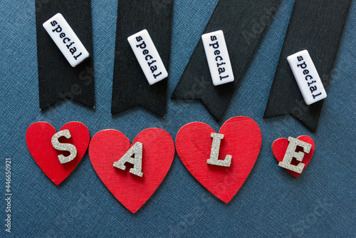 retro black chalk tags, hand painted red hearts, wooden letters with the word sale on a dark background - including plastic word beads with special