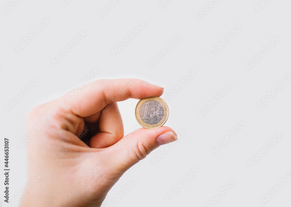 one euro coin in woman's hand on white background