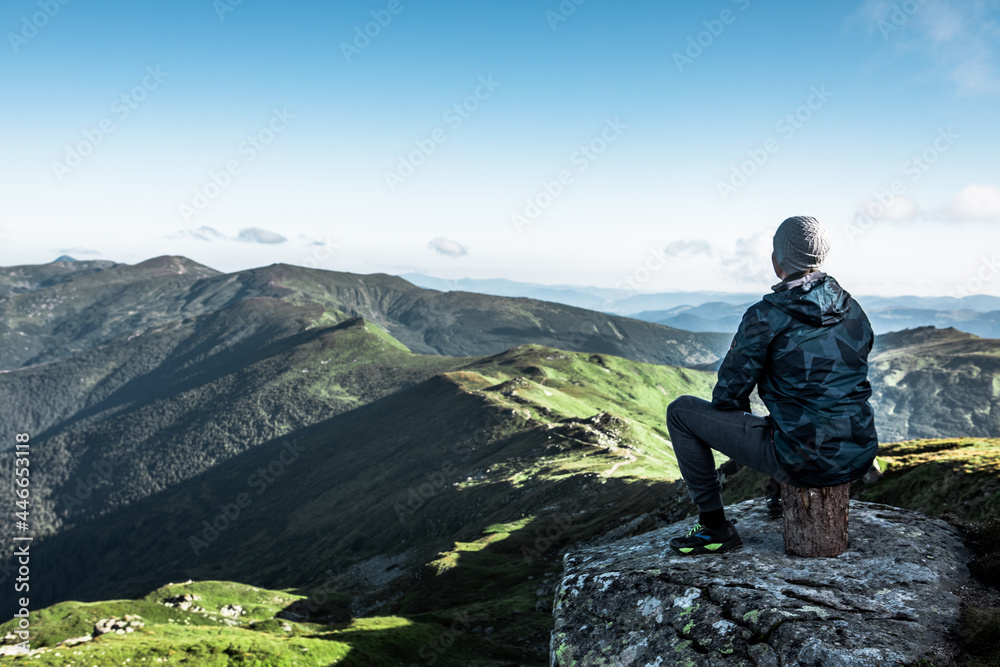 man sitting at the top of the mountain enjoying the view man sitting at the top of the mountain enjoying the view