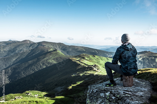man sitting at the top of the mountain enjoying the view