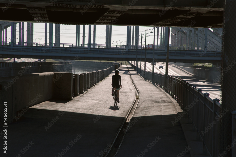 Fototapeta premium View of an athlete cyclist training in the morning in the city on the waterfront. Cycling in the city. Preparing for the competition.