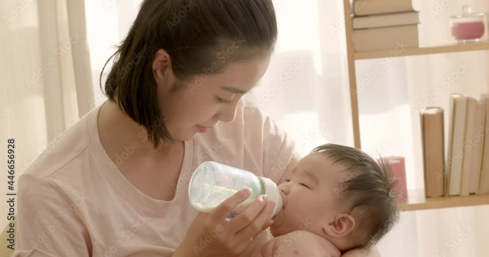 Young mom feeding baby girl with bottle,4K