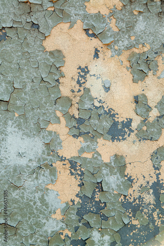 Concrete wall painted with gray-green paint, badly cracked old paint on metal. Vertical photo.