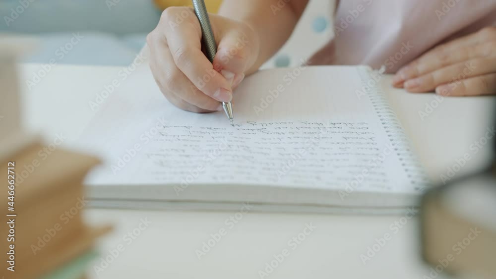 Close-up slow motion of hand writing in copybook while student doing homework creating essay indoors at home. Education and knowledge concept.