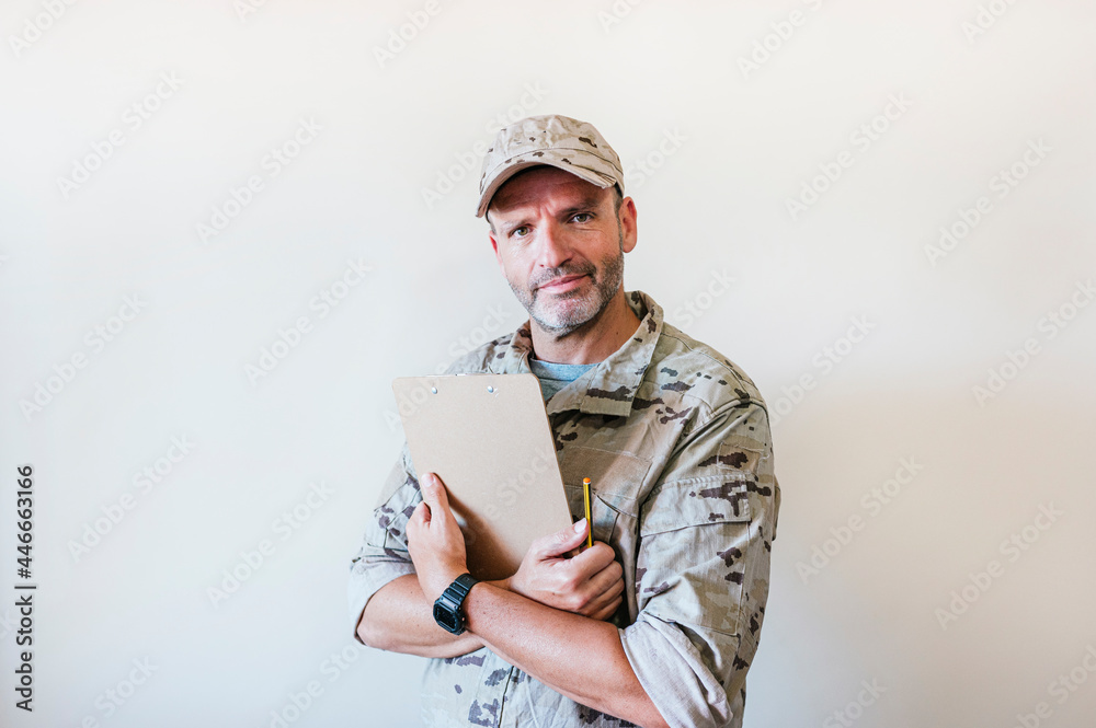 Caucasian man in camouflaged military uniform holding notebook. Caucasian man in camouflaged military uniform holding notebook.