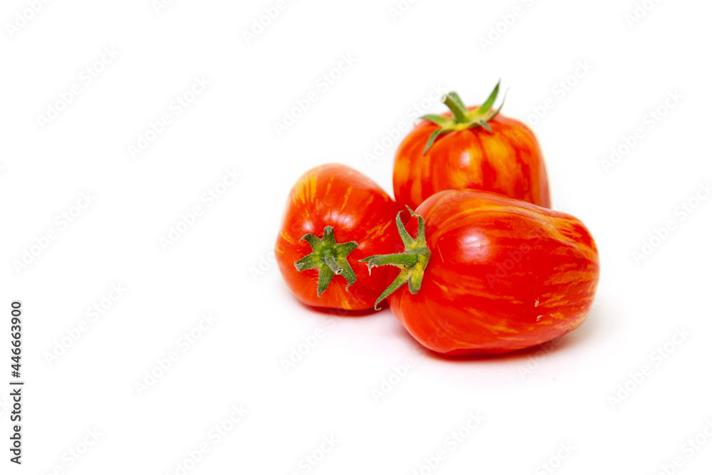 Three red tomatoes with yellow stripes lie on white background Three red tomatoes with yellow stripes lie on white background
