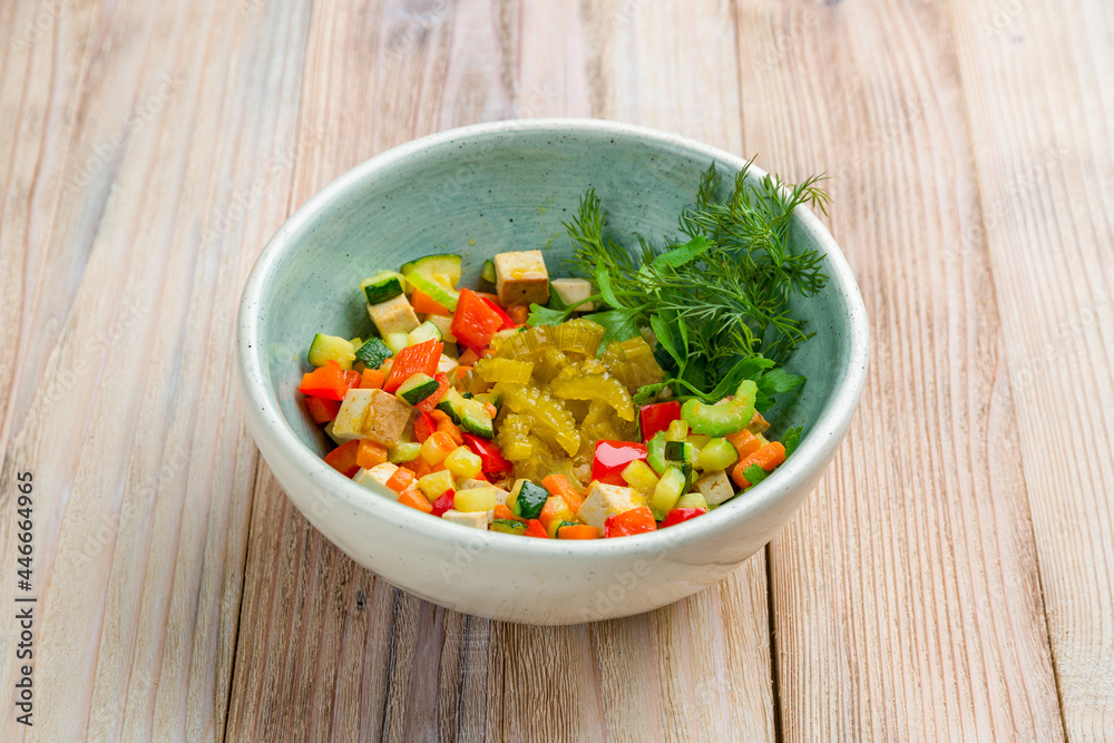 Bowl with tofu and vegetables on wooden table Bowl with tofu and vegetables on wooden table