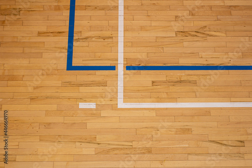 The worn wooden floor of the sports basketball hall with colorful marking lines.