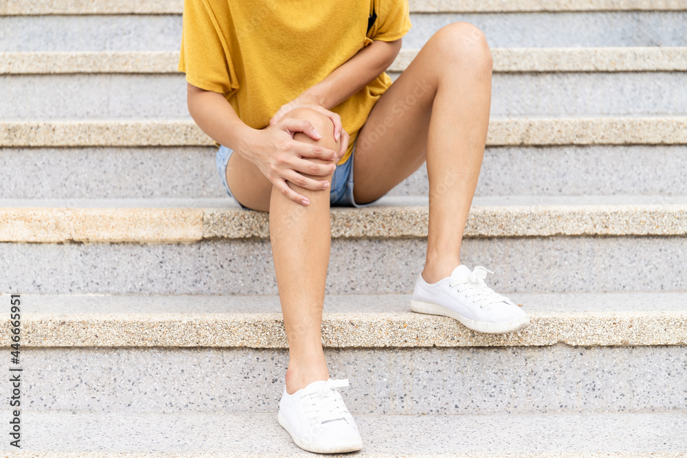 Obraz premium woman resting on the stairs holding her knees As his legs trembled, he couldn't go down the stairs. The concept of Guillain-Barre's disease and numbness or side effects of vaccines.