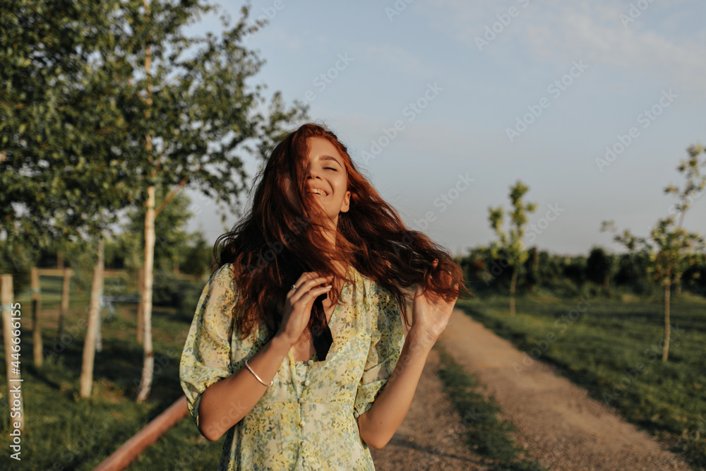 Joyful redhead in stylish summer green and yellow clothes smiling with closed eyes on a daytime at the nature Joyful redhead in stylish summer green and yellow clothes smiling with closed eyes on a daytime at the nature
