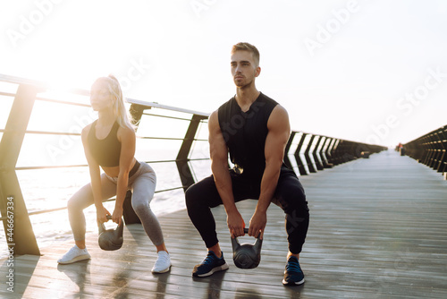 Healthy lifestyle. Young beautiful couple doing sports exercises at the beach pier. Sport, Active life.