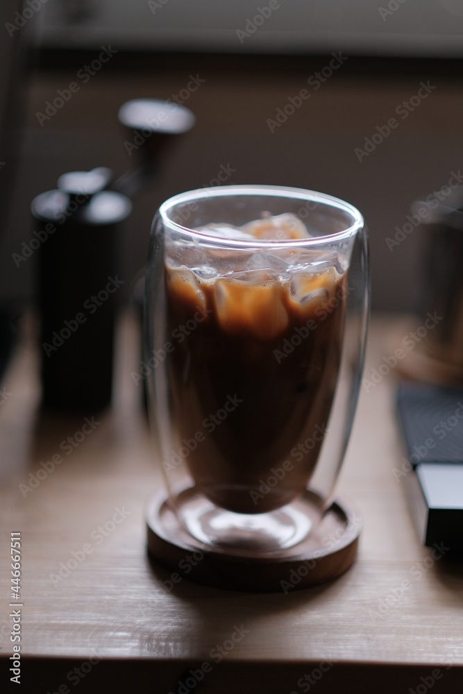 Ice coffee in a tall glass with cream poured over and coffee beans on a old rustic wooden table. Cold summer drink. Ice coffee in a tall glass with cream poured over and coffee beans on a old rustic wooden table. Cold summer drink.