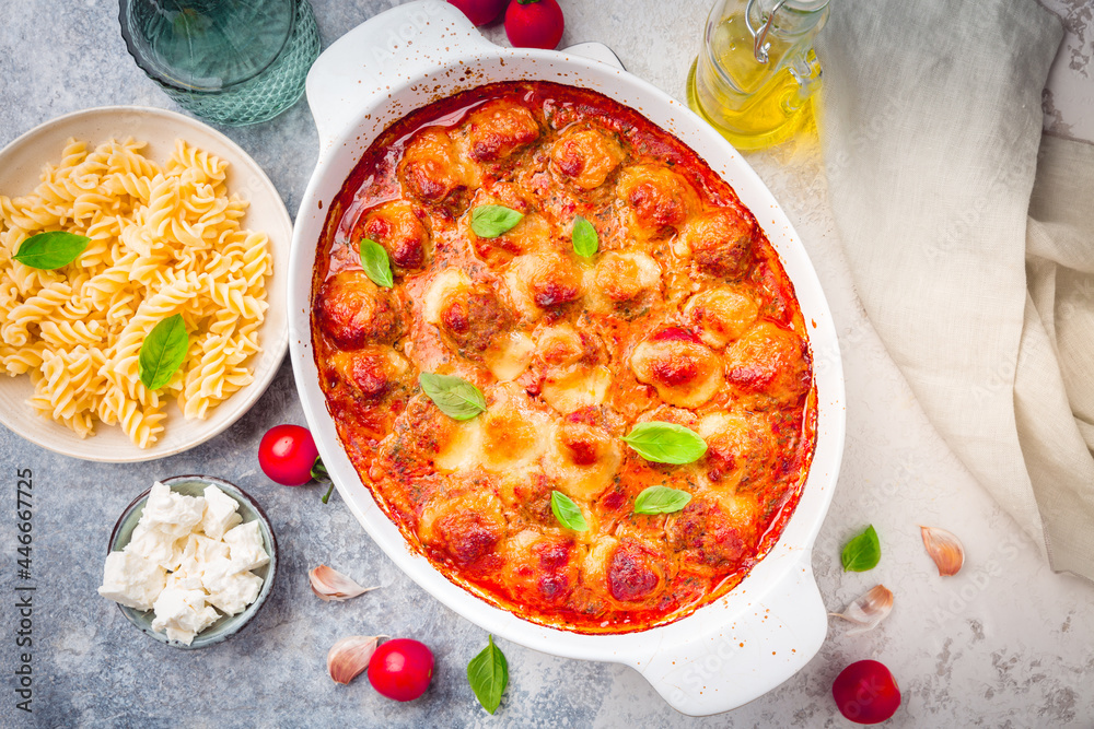 Homemade meatballs in tomato mozzarella sauce with basil and pasta in casserole