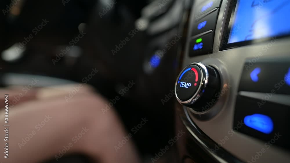 The woman rotates the temperature control knob of the air conditioning system in the car. Cooling and heating of the car interior
