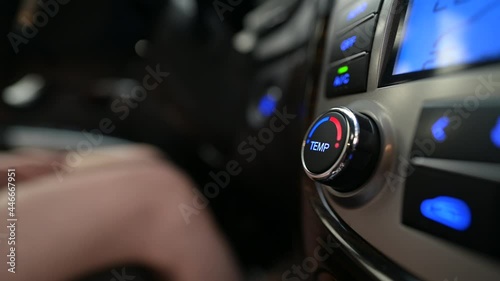 The woman rotates the temperature control knob of the air conditioning system in the car. Cooling and heating of the car interior