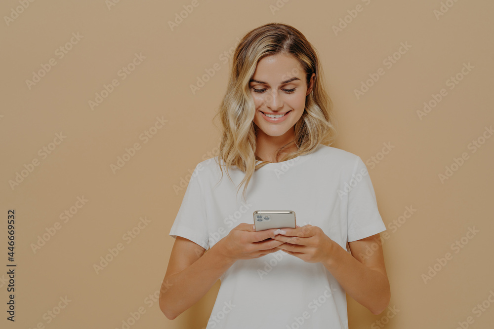 Young happy girl using smartphone, chatting with boyfriend in social media and smiling Young happy girl using smartphone, chatting with boyfriend in social media and smiling
