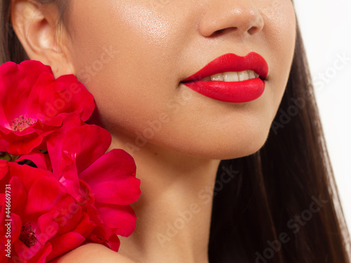Smiling young girl. Beauty face closeup. Sexy lips. Beauty natural lip makeup detail. Beautiful make-up close-up. Sensual open mouth with teeth. Lipstick and lipgloss. Flowers