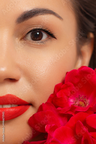 Close-up beauty of half female face with creative fashion evening make-up. Black arrows on the eyes and extremely long eyelashes, on plump lips matte scarlet lip color. Well-groomed skin after spa