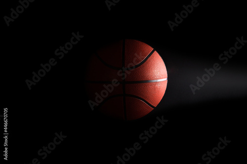 Basketball on black background in the dark with copy space © Aida Servi