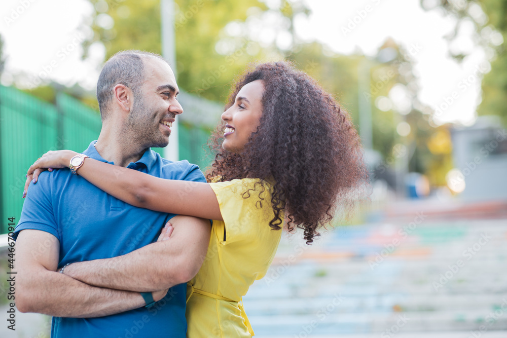 White man and Black curly Afro woman are having a great time, they are laughing and looking each other.