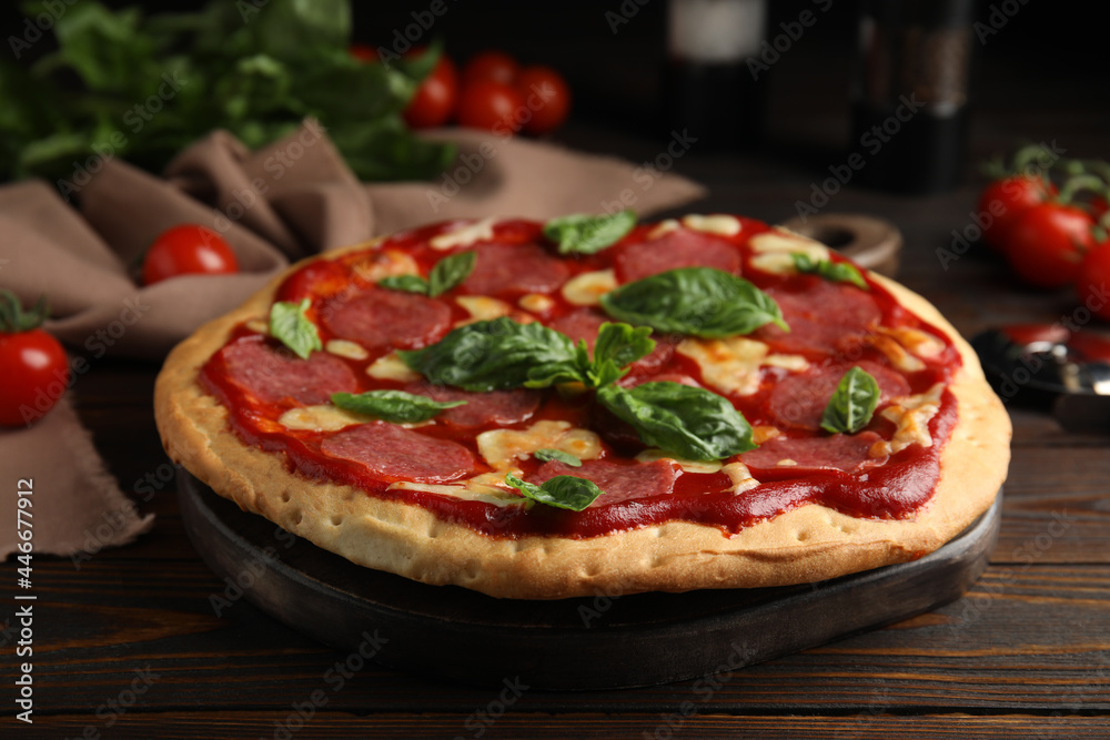 Pita pizza with pepperoni, cheese and basil on wooden table, closeup