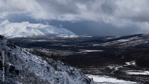 Bild auf Leinwand Snowy hill and green plain under white clouds