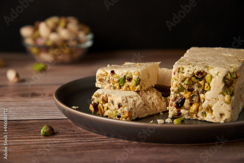 Organic halva with pistachios on a wooden surface. Traditional middle eastern sweets. Jewish, turkish, arabic oriental national dessert. Turkish delight concept. Natural vegan product. Copy space. photo