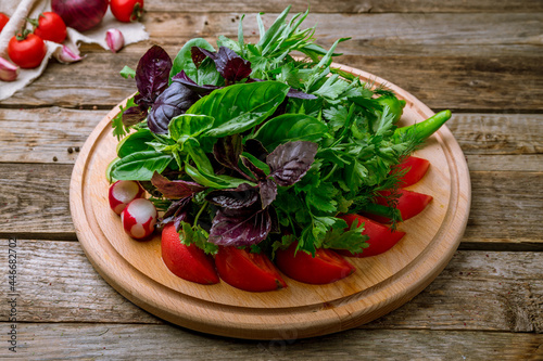 fresh vegetables and greens on a plate on wooden table