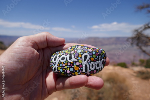 Hand hold kindness stone in front of out of focus Grand Canyon background