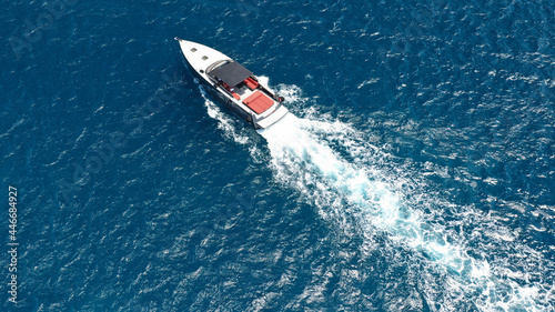 Aerial drone photo of small luxury speed boat cruising in deep blue waters of Mykonos island, Cyclades, Greece