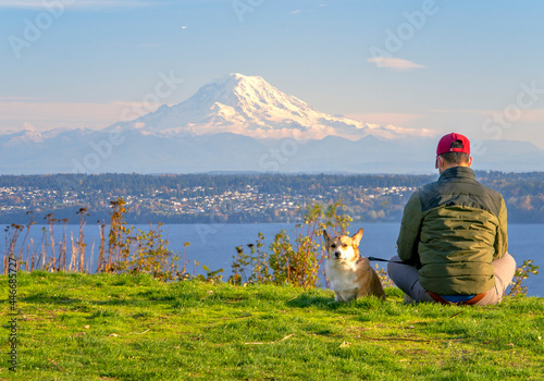 A Man with hist Pet Corgi Sitting and Enjoying the Scenery of Mount Rainier from Vashon Island photo