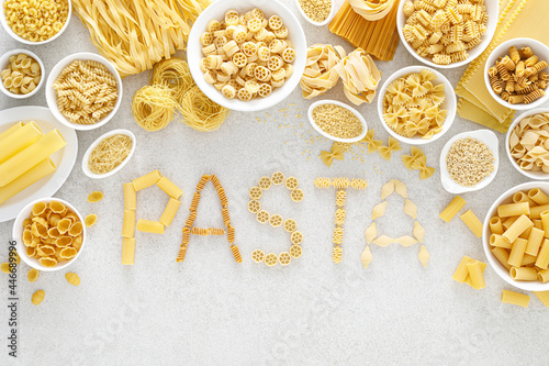 Pasta. Various kinds of uncooked pasta and noodles over stone background, top view with copy space for text. Italian food culinary concept. Collection of different raw pasta on cooking table