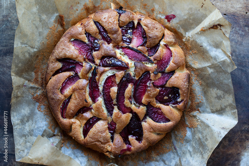 Round freshly baked plum cake on the wooden board photo