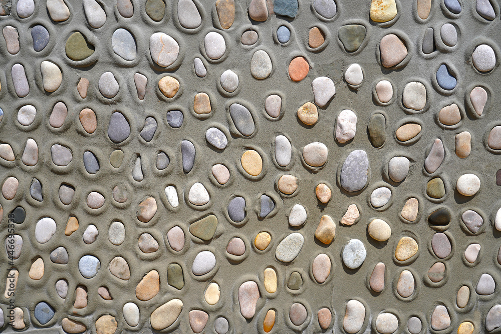 A gray concrete wall made of cement with a lot of sea stones and pebbles of different colors A gray concrete wall made of cement with a lot of sea stones and pebbles of different colors