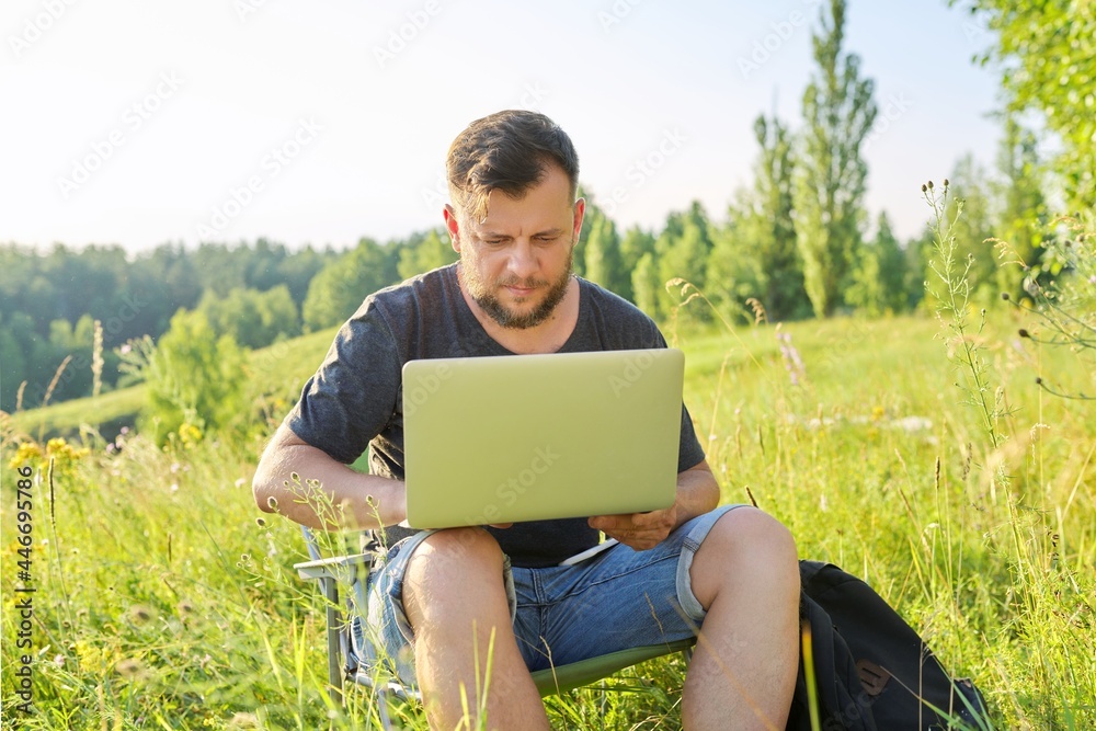 Middle-aged man with backpacks with laptop in nature Middle-aged man with backpacks with laptop in nature
